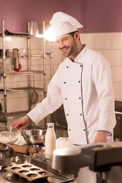 Lächelnder Konditor steht in Restaurantküche am Tresen — Stockfoto