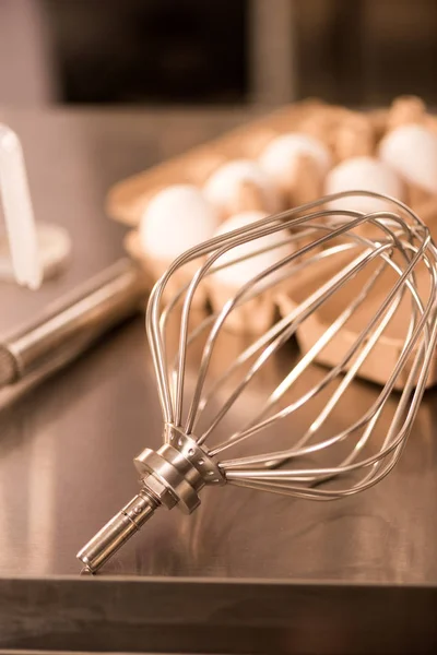Close up view of whisk and raw eggs for making cream on counter in restaurant — Stock Photo