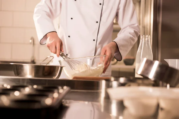 Vista parcial de confeiteiro com whisk fazendo massa na cozinha do restaurante — Fotografia de Stock