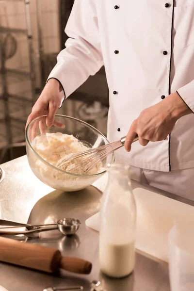 Vista parcial de confeiteiro com whisk fazendo massa na cozinha do restaurante — Fotografia de Stock