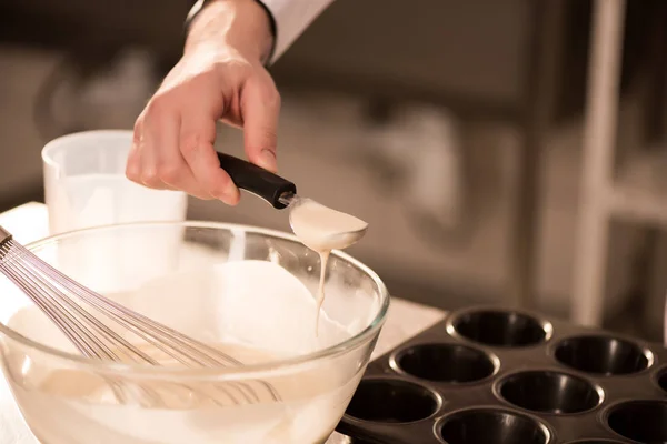 Vue partielle du confiseur versant la pâte dans des formes de cuisson — Photo de stock