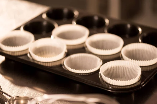 Vista de cerca de las formas vacías de hornear con papel de hornear para cupcakes - foto de stock