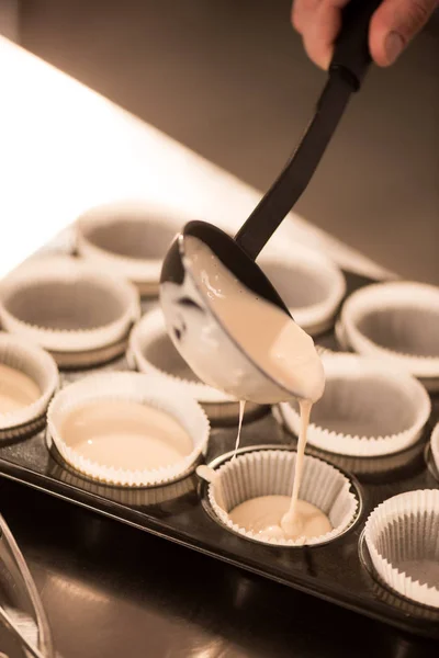 Tiro cortado de massa de confeiteiro derramando em formas de cozimento — Fotografia de Stock