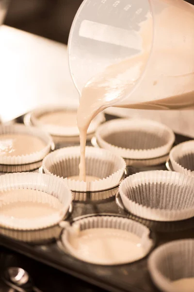 Close up view of pouring raw dough into baking forms process — Stock Photo