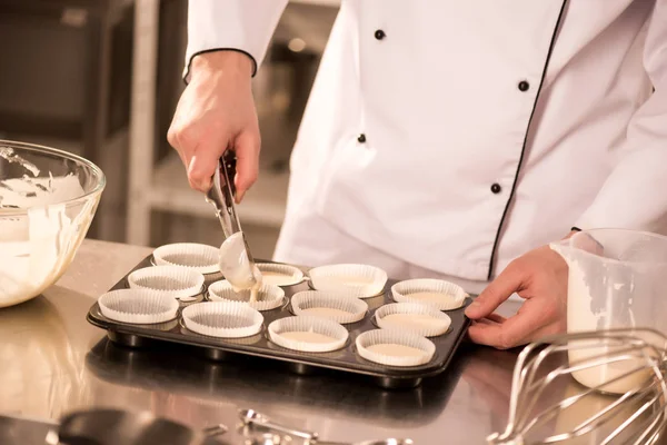 Abgeschnittener Schuss Konditor gießt Teig in Backformen — Stockfoto