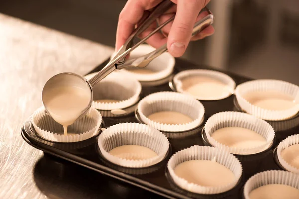 Tiro cortado de massa de confeiteiro derramando em formas de cozimento — Fotografia de Stock