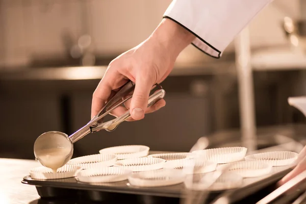 Обрезанный кадр кондитера, наливающего тесто в хлебопекарные формы — стоковое фото