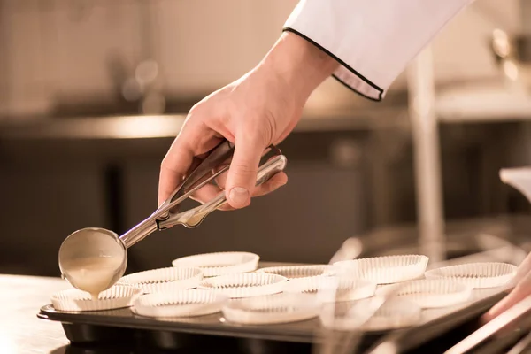 Tiro cortado de massa de confeiteiro derramando em formas de cozimento — Fotografia de Stock