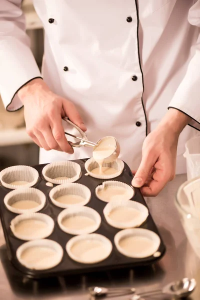 Plan recadré de confiseur verser la pâte dans des formes de cuisson — Photo de stock