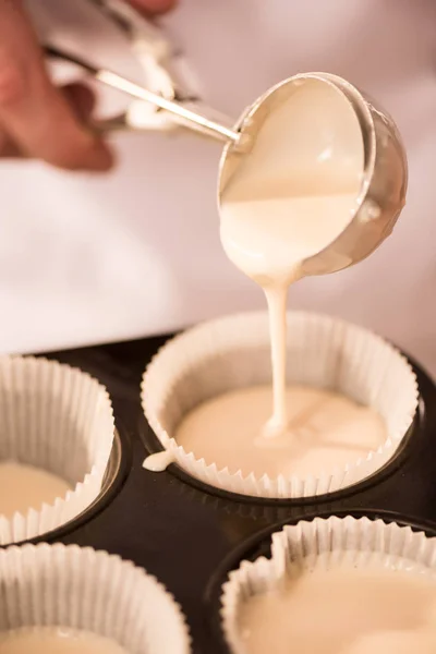 Tiro cortado de massa de confeiteiro derramando em formas de cozimento — Fotografia de Stock