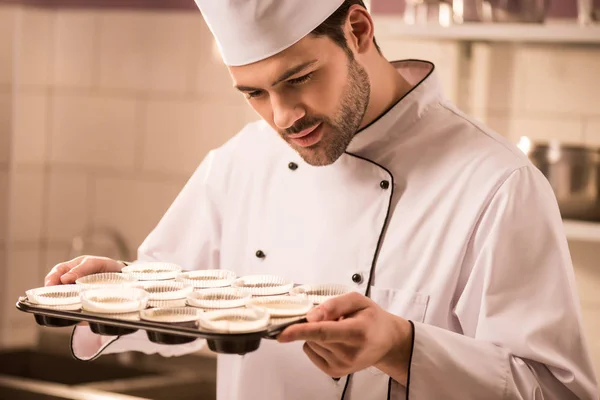 Confectioner checking dough in baking forms in restaurant kitchen — Stock Photo