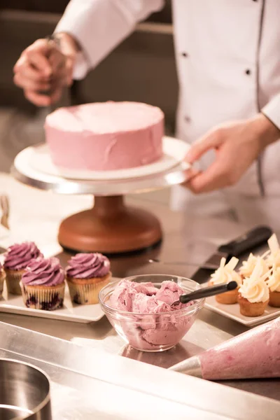 Tiro recortado de confitero haciendo pastel en la cocina del restaurante - foto de stock