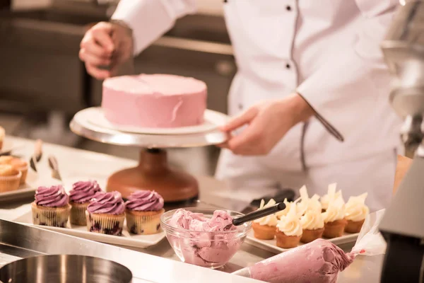 Tiro recortado de confitero haciendo pastel en la cocina del restaurante - foto de stock