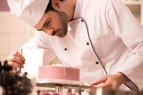 Confeiteiro focado fazendo bolo doce na cozinha do restaurante — Fotografia de Stock