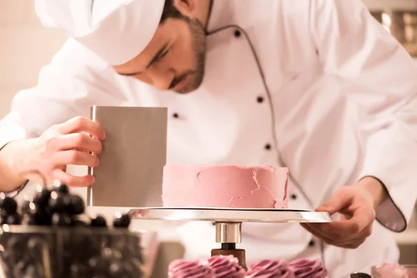 Confitero enfocado haciendo pastel dulce en la cocina del restaurante - foto de stock