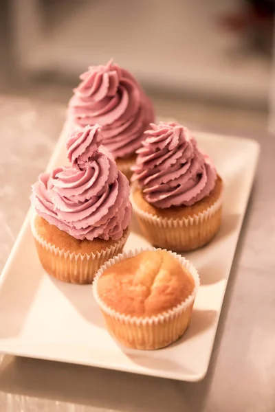 Close up view of sweet cupcakes on plate on counter in restaurant kitchen — Stock Photo