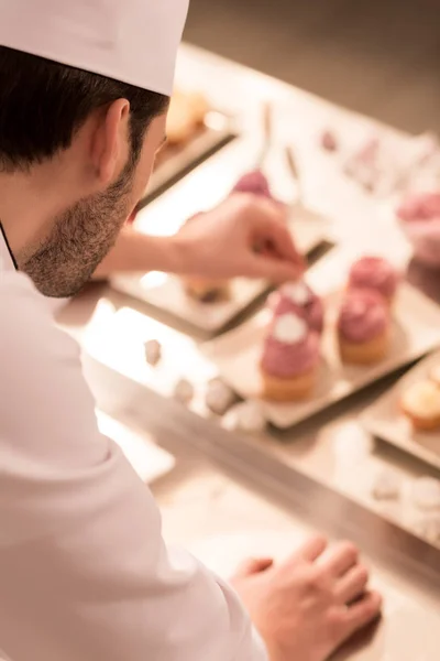 Foco seletivo de confeiteiro decorar cupcakes na cozinha do restaurante — Fotografia de Stock