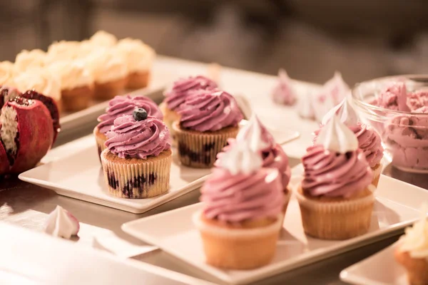 Close up view of sweet cupcakes on plates on counter in restaurant kitchen — Stock Photo