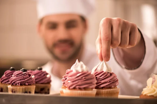 Selective focus of confectioner decorating cupcakes in restaurant kitchen — Stock Photo