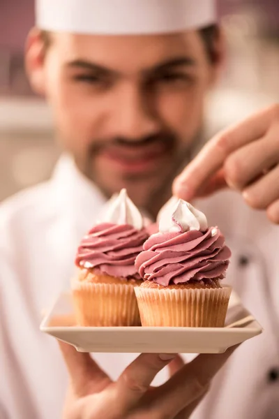 Selective focus of confectioner decorating cupcakes in restaurant kitchen — Stock Photo