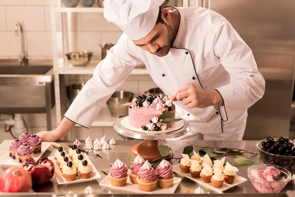 Porträt eines Konditors, der Kuchen in der Restaurantküche dekoriert — Stockfoto