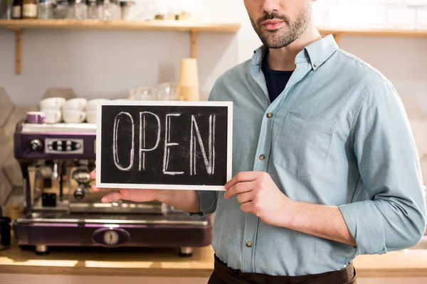 Vista parziale di barista con lavagna aperta in mano in caffetteria — Foto stock