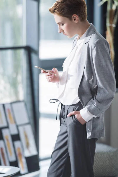 Belle jeune créateur de mode en utilisant smartphone au bureau — Photo de stock