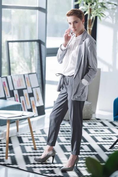 Atractivo joven diseñador de moda hablando por teléfono en la oficina - foto de stock