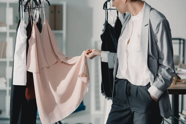 Plan recadré de jeune créateur de mode examinant la qualité des vêtements sur cintres — Photo de stock