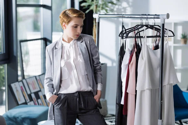 Junge Modedesignerin betrachtet Kleidungsstücke am Regal — Stockfoto