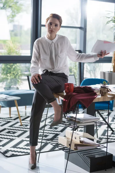 Молодий дизайнер моди з паперовими роботами сидить на робочому столі — стокове фото