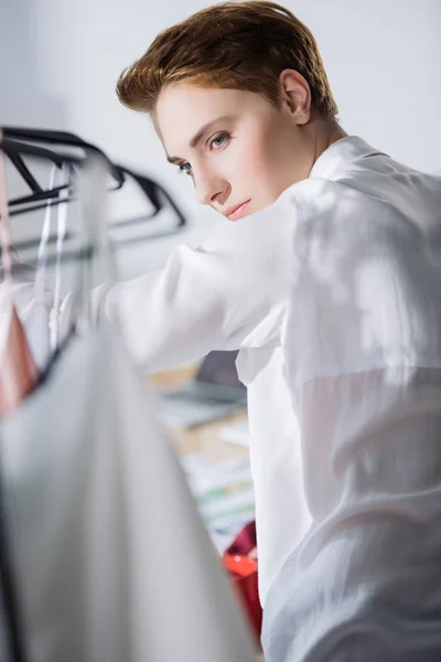 Jeune créateur de mode à la recherche de robes sur rack — Photo de stock