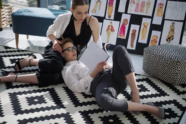Young fashion designers lesbian couple working together on floor of office — Stock Photo