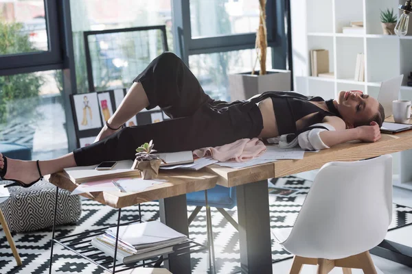 Overworked stylish fashion designer sleeping on work desk — Stock Photo