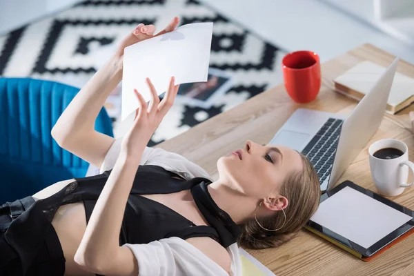 Attraktive Modedesignerin auf Schreibtisch liegend und Skizze anschauend — Stockfoto