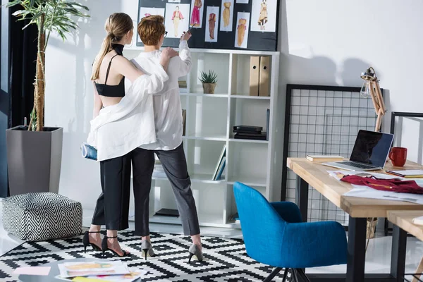 Young fashion designers looking at clothing sketches — Stock Photo