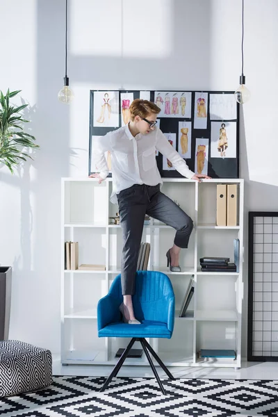 Stylische attraktive Modedesignerin auf Bürostuhl stehend — Stockfoto