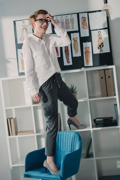 Счастливый привлекательный модельер, стоящий на стуле в офисе — стоковое фото