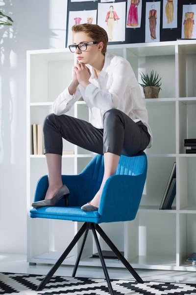 Estilista elegante pensativo sentado na cadeira no escritório moderno — Fotografia de Stock