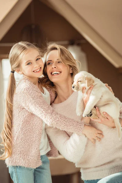 Mother and little daughter playing with adorable labrador puppy — Stock Photo