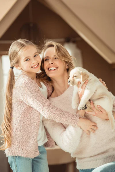 Mère et petite fille jouant avec adorable chiot labrador — Photo de stock