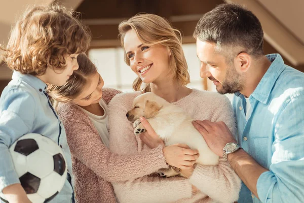 Young family with adorable labrador puppy in front of cardboard house — Stock Photo