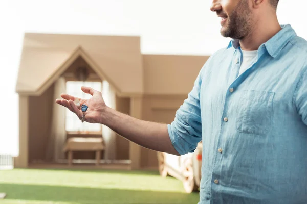 Glücklicher Mann mit Schlüssel für neues Kartonhaus isoliert auf weißem Grund — Stockfoto