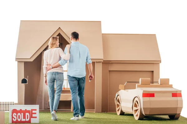 Rear view of couple walking to their new cardboard house isolated on white — Stock Photo