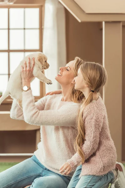 Mãe e filhinha brincando com adorável filhote de cachorro labrador — Fotografia de Stock