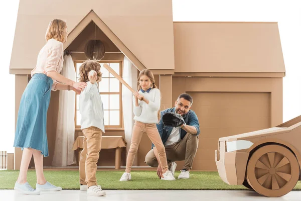 Young family playing baseball together on yard of cardboard house isolated on white — Stock Photo