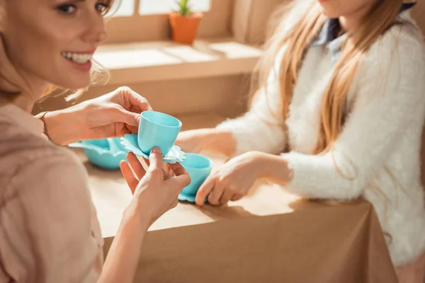 Cropped shot of mother and daughter having tea party in cardboard house — Stock Photo