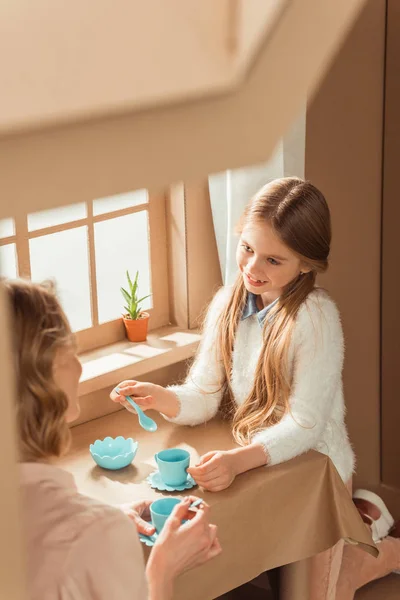 Мати і красива дочка проводять чайну вечірку в картонному будинку — стокове фото