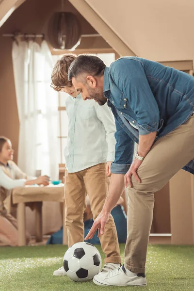 Happy father teaching his som to play soccer on grass — Stock Photo