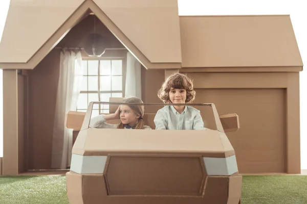 Дети катаются на картонной машине перед домом — стоковое фото